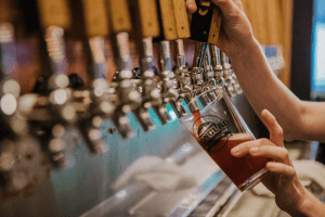 Beer being poured beneath line of beer taps 
