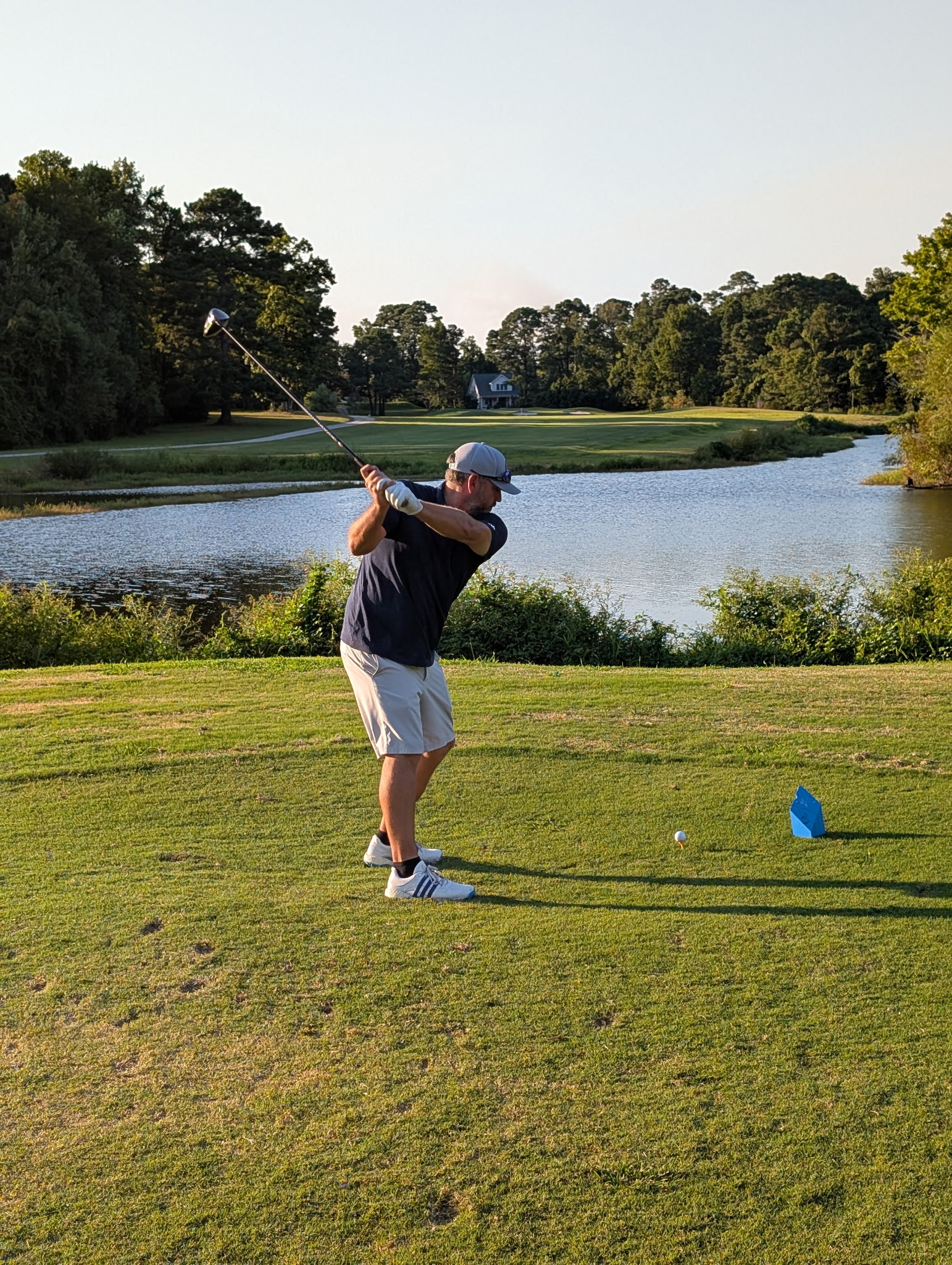 Picture of head pro hitting a drive on hole 8 over the water. 